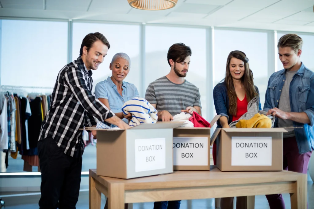 Creative business team sorting clothes in donation box