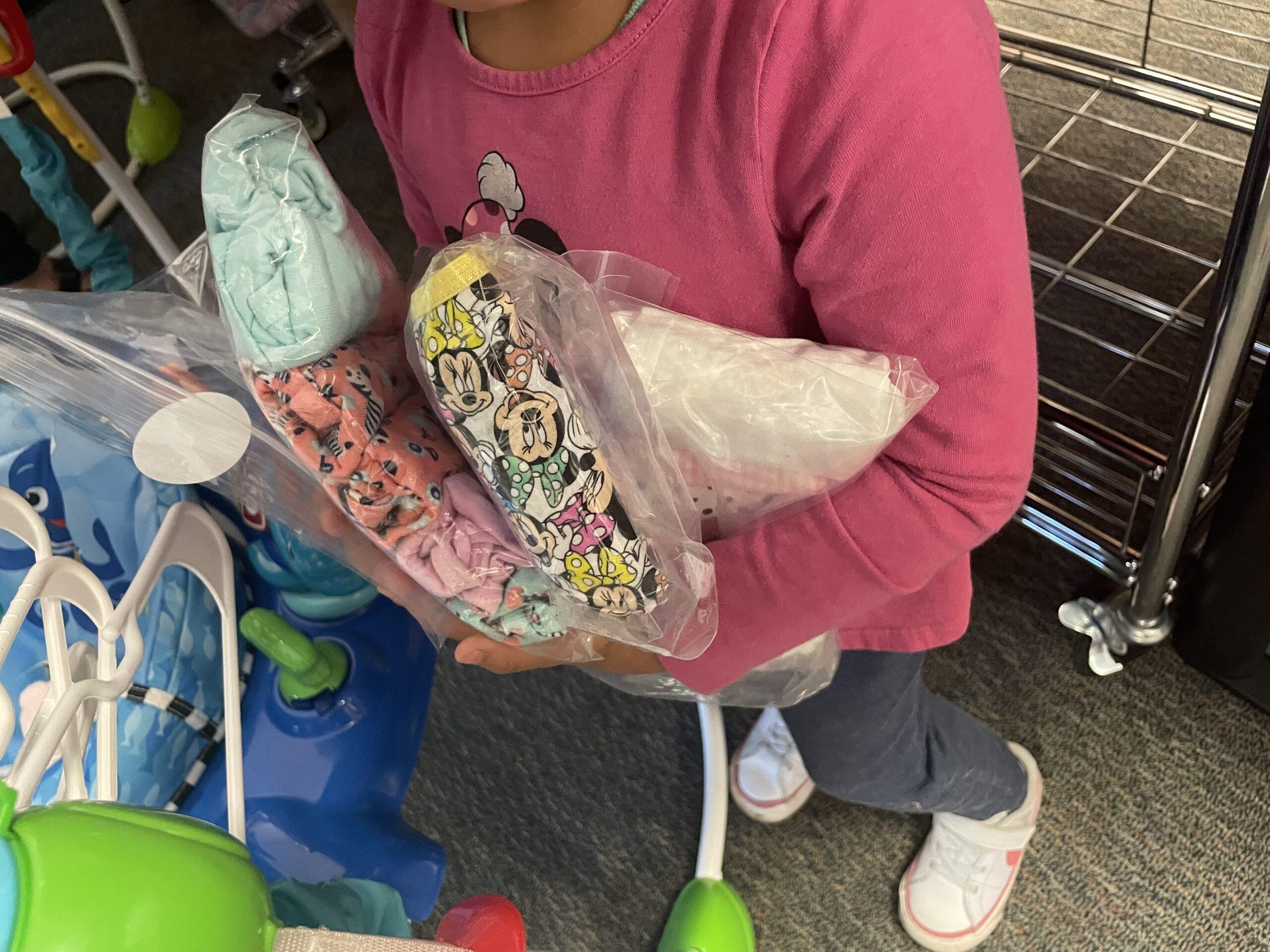 Child holding packs of UFE underwear.